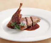 Ente mit Apfel-Zwiebel-Füllung angeschnitten auf weißem Teller