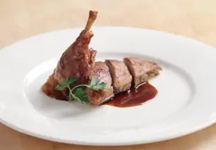 Ente mit Apfel-Zwiebel-Füllung angeschnitten auf weißem Teller
