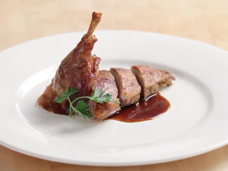 Ente mit Apfel-Zwiebel-Füllung angeschnitten auf weißem Teller