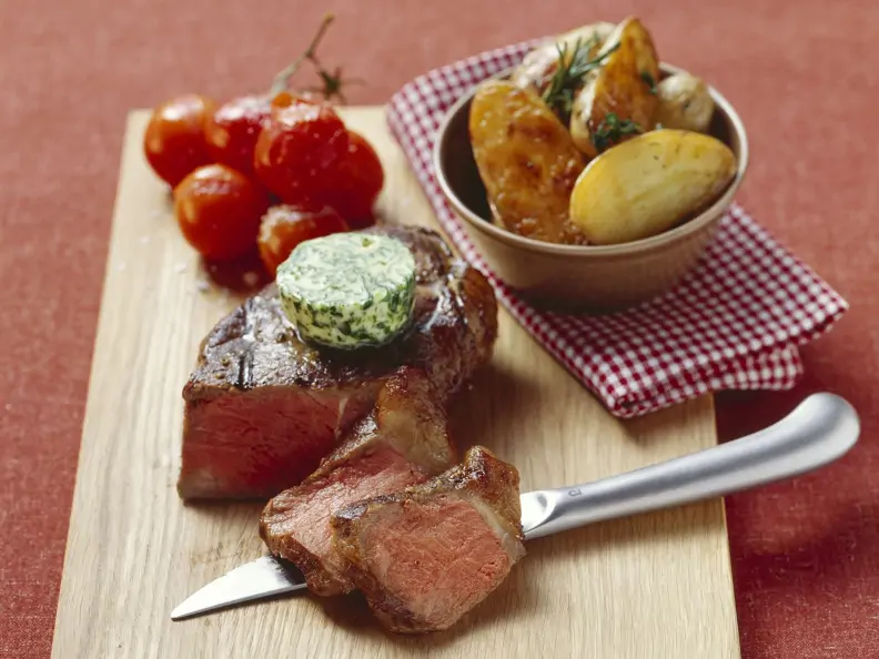 Steak mit Kräuterbutter, gebackenen Kartoffeln und Tomaten