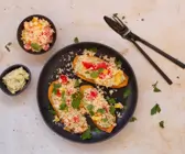 Süßkartoffeln auf einem schwarzen Teller belegt mit Hummus und Couscoussalat