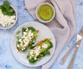 Zwei Süßkartoffelscheiben belegt mit Avocadomus, Feldsalat und Schafskäse