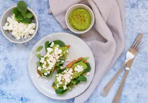 Zwei Süßkartoffelscheiben belegt mit Avocadomus, Feldsalat und Schafskäse