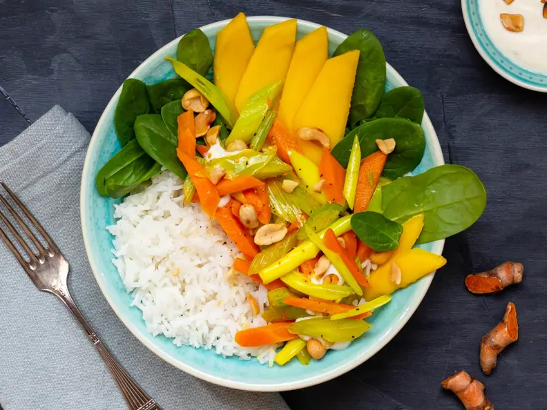 Reisbowl mit Kurkumagemüse, Babyspinat, Erdnussdip und Mango