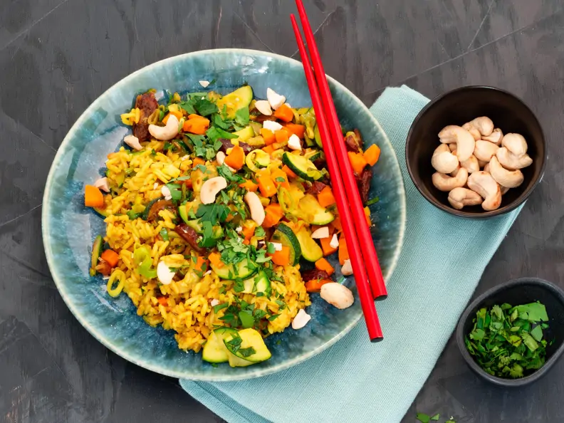 Blaue Schale mit Gemüse und Reis, Kräutern und Cashewkernen 