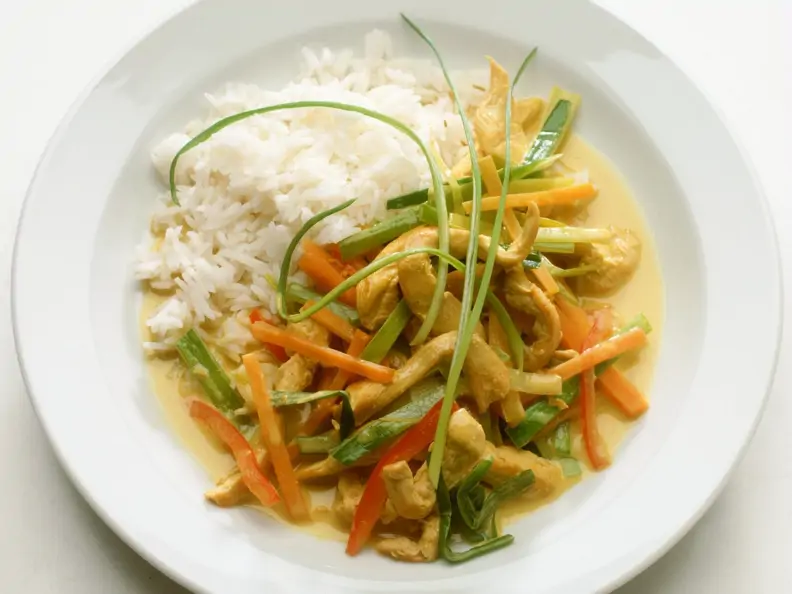 Hähnchenstreifen mit Gemüse und Kokossoße aus dem Wok, dazu Reis