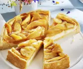 Käsekuchen mit Apfelhaube und Blümchen im Hintergrund