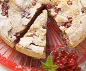 Johannisbeerkuchen mit Baiser auf einer roten Dekorplatte