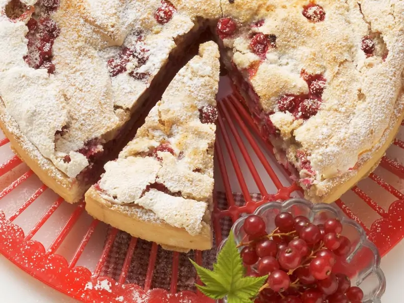 Johannisbeerkuchen mit Baiser auf einer roten Dekorplatte