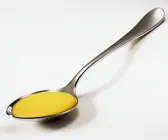 Gelbe Currysoße auf einem silbernen Löffel