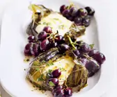 Weinblätter mit Mozzarellafüllung dazu Trauben und Anchovies