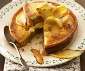 Saftiger Apfel-Käsekuchen mit Boden auf einem hellen Teller mit grünem Dekor