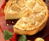 Käsekuchen mit Äpfeln auf rotem Kuchenteller