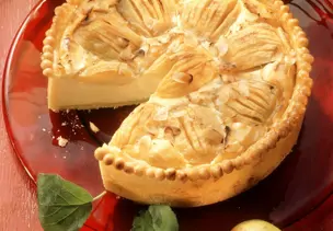 Käsekuchen mit Äpfeln auf rotem Kuchenteller