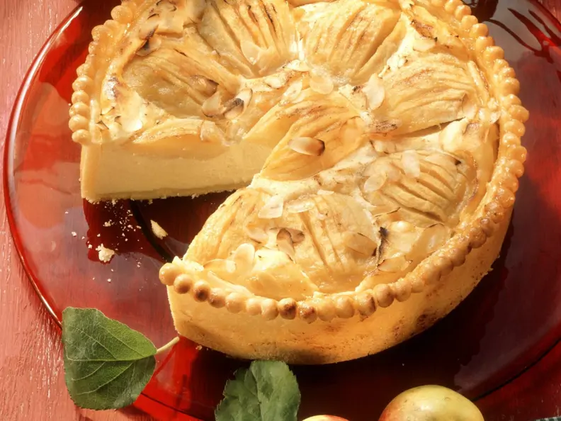 Käsekuchen mit Äpfeln auf rotem Kuchenteller