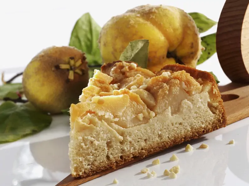Quittenkuchen mit Quitten im Hintergrund 