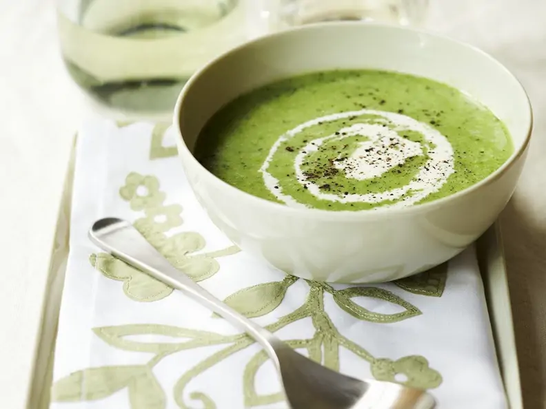 Erbsencremesuppe mit Minze in weißer Schüssel