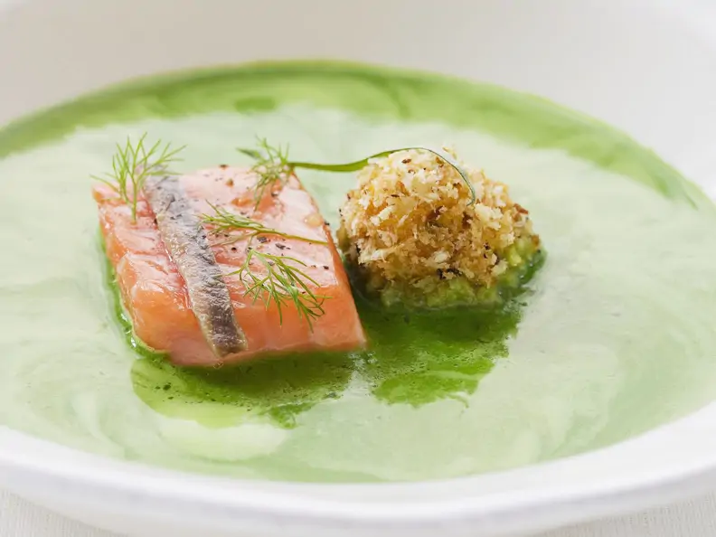 Suppe aus frischen Kräutern mit Lachs und Heringskrokette