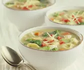 Drei weiße Schälchen gefüllt mit bunter Gemüsesuppe und Tortellini