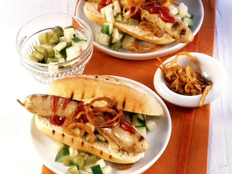 Hot Dog mit Grillwürstchen, Gurken und Röstzwiebeln