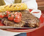 T-Bone-Steak mit gegrilltem Mais und Cherrytomaten