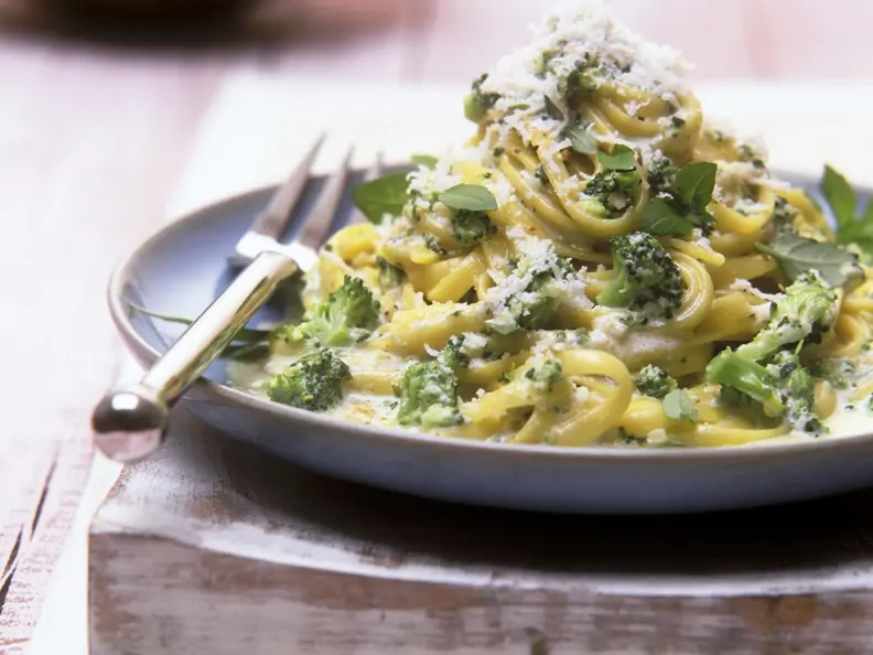 Pasta mit sahniger Brokkolisoße mit Parmesam bestreut auf blauem Teller