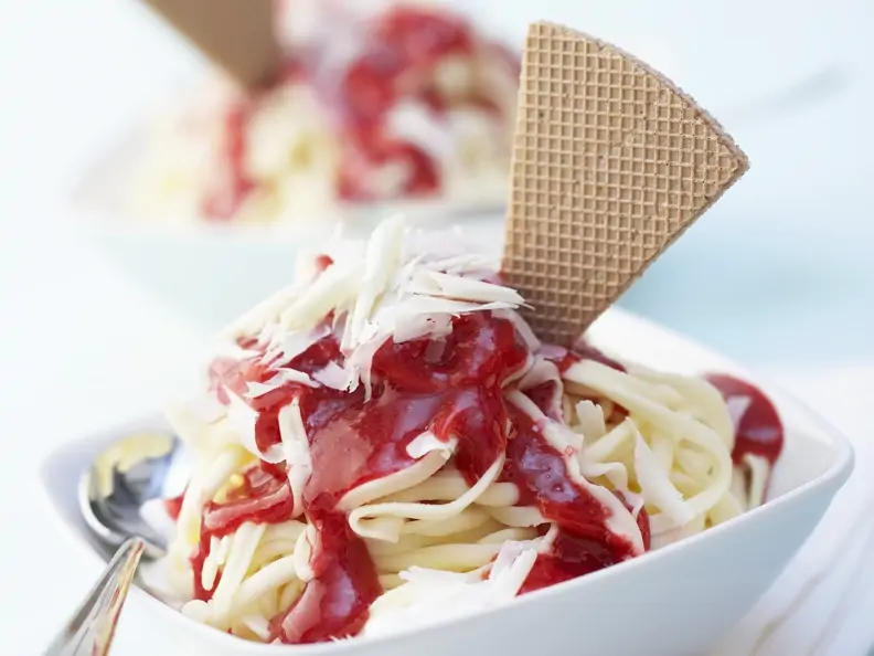 Spaghetti-Eis mit Erdbeersoße und weißen Schokoraspeln