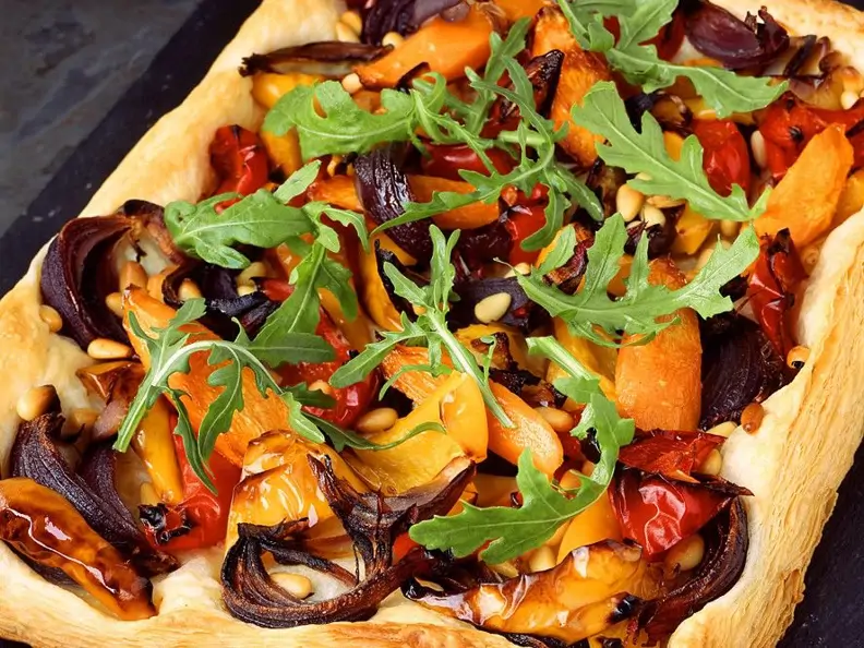 Gemüsepizza mit Rucola auf dem Blech