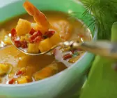 Suppe in türkiser Schale, Löffel mit Gemüse und Garnele