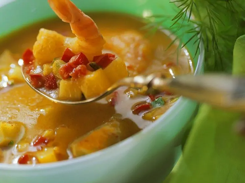 Suppe in türkiser Schale, Löffel mit Gemüse und Garnele