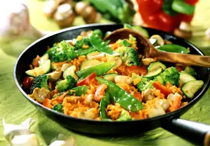 Reis-Gemüsepfanne mit Paprika im Hintergrund
