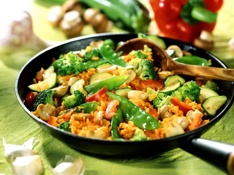 Reis-Gemüsepfanne mit Paprika im Hintergrund