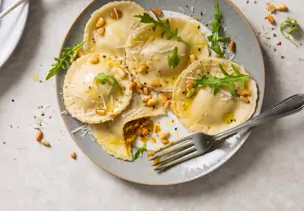 Kürbis-Ravioli mit Pinienkernen und Rucola