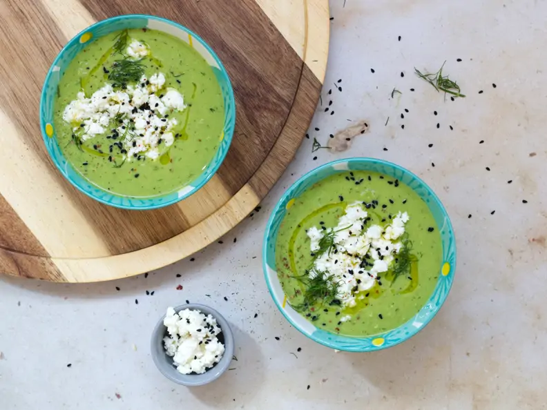 Grüne Suppe in zwei Schalen mit weißem Topping