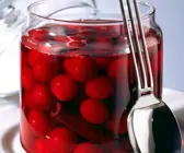 Rotweinkirschen im Glas, daneben Deckel und Löffel