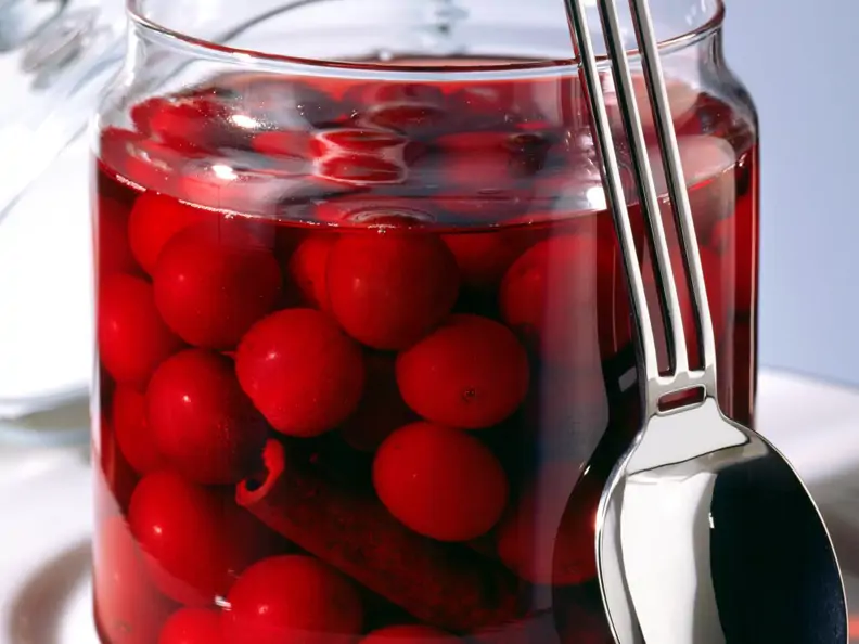 Rotweinkirschen im Glas, daneben Deckel und Löffel