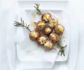 Umwickelte Feigen mit Ricotta-Nuss-Füllung auf einem Rosmarinspieß