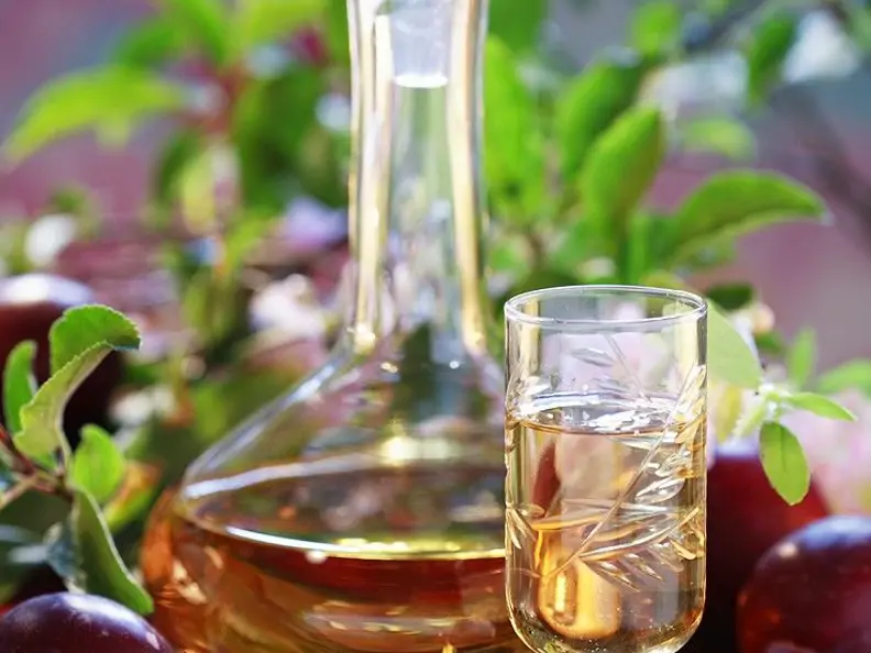 Likör in einem Schnapsglas mit einer gefüllten Karaffe im Hintergrund