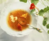 Gemüsebouillon mit Karottenstreifen und Blüten