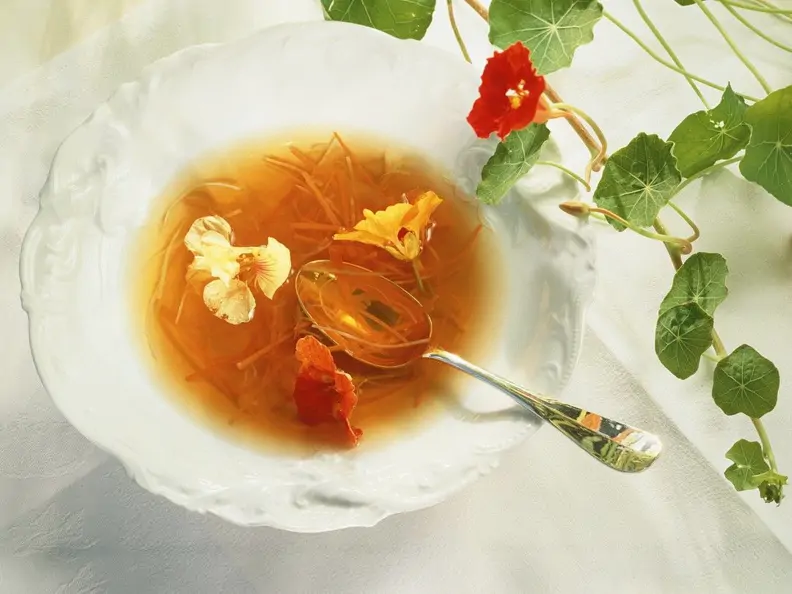 Gemüsebouillon mit Karottenstreifen und Blüten