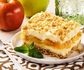 Geschichteter Apfel-Käsekuchen mit Knuspermüsli auf weißem Teller