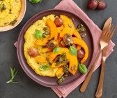 Gebackene Kürbisspalten mit roten Weintrauben auf cremiger Polenta