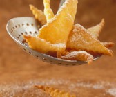 Schmalzgebäck mit Puderzucker auf Schaumkelle