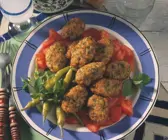 Zucchini-Bratlinge nebst Tomaten und Peperoni auf blauem Teller
