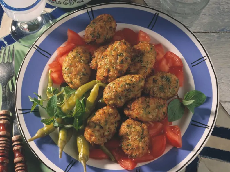 Zucchini-Bratlinge nebst Tomaten und Peperoni auf blauem Teller