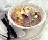 Gemüsesuppe in weißer Schale mit Nudeln und Fisch