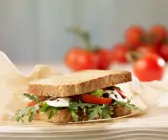 Sandwich aus Vollkorntoast mit Mozzarella, Tomate und Rucola